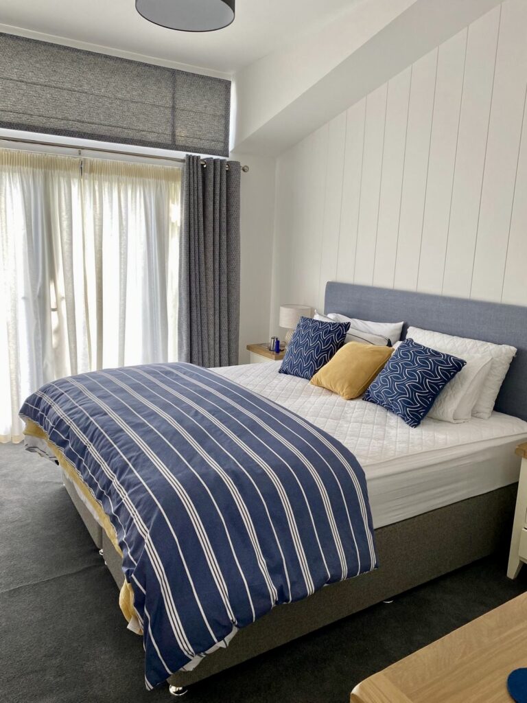 Bespoke Lodge Double bed with blues and white striped quilt and blue, white and yellow pillows