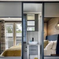 Lakewood Lodge double bedroom - Bed and view of decking reflected in Mirrors of wardrobe, with small vanity unit