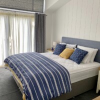 Bespoke Lodge Double bed with blues and white striped quilt and blue, white and yellow pillows